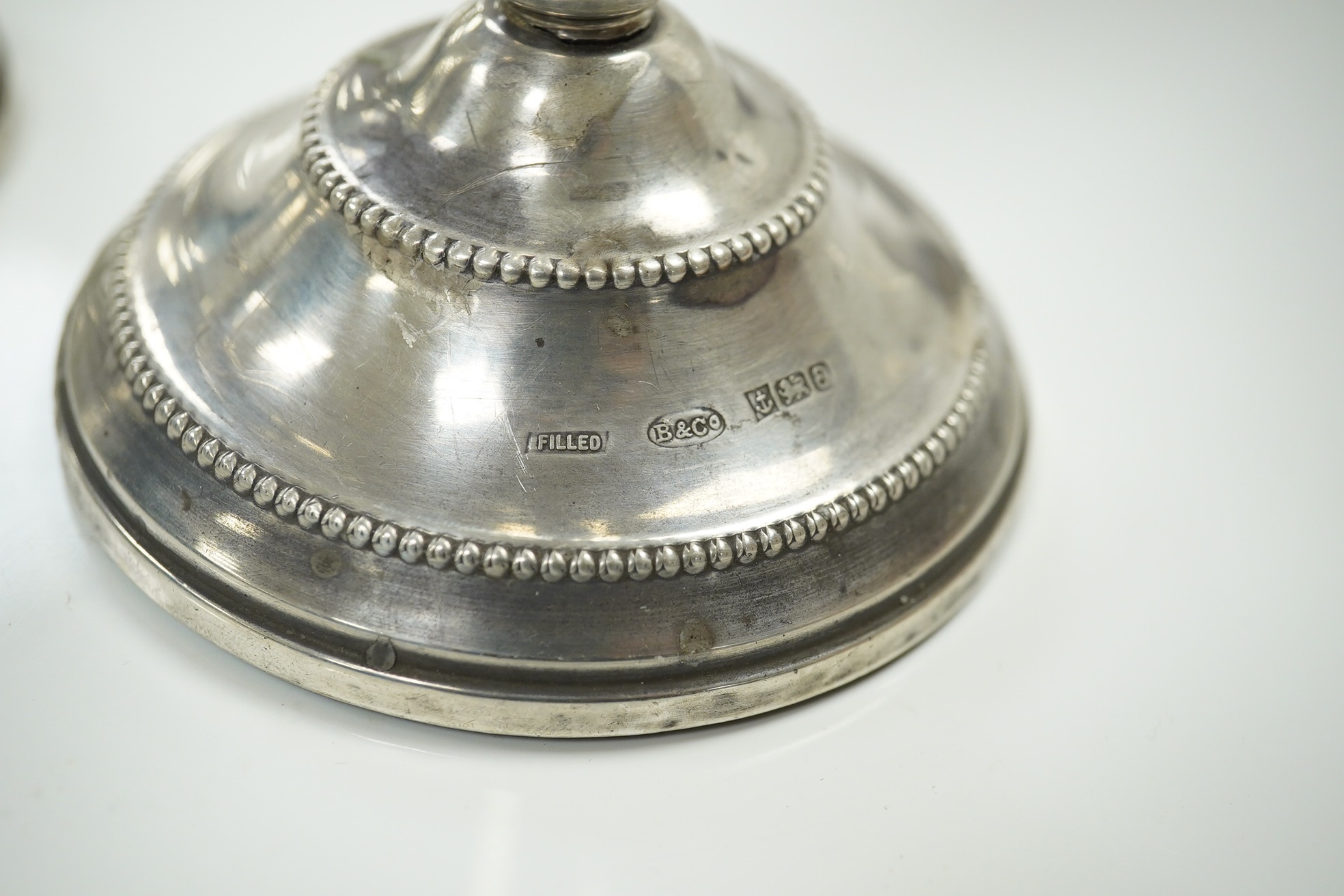 A pair of modern loaded silver candlesticks, 18cm high, an embossed silver mounted photograph frame, 20cm and a plain rectangular photograph frame, 16cm. Condition - fair to good